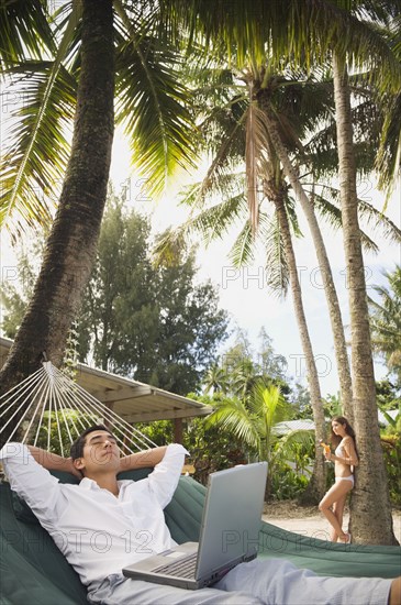 Asian man with laptop in hammock