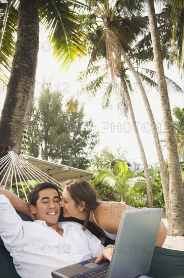 Asian man with laptop in hammock