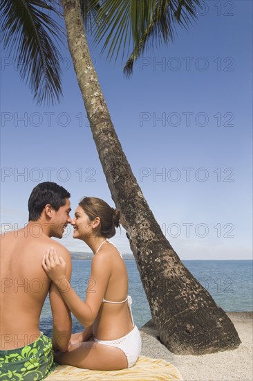 Asian couple sitting on beach