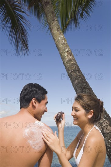 Asian woman applying sunscreen to boyfriend