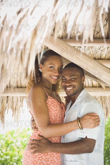 African American couple hugging in grass hut