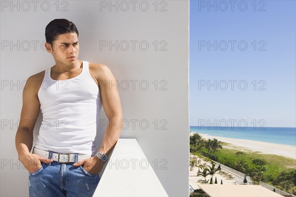 Hispanic man leaning on balcony wall