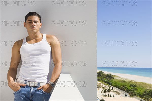 Hispanic man leaning on balcony wall