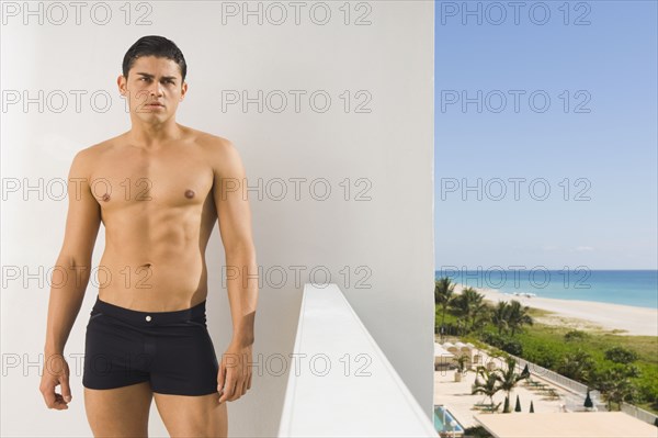 Hispanic man in bathing suit on balcony