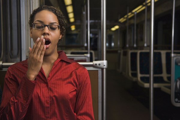 African businesswoman yawning on train