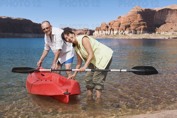 Multi-ethnic senior couple next to kayak in water