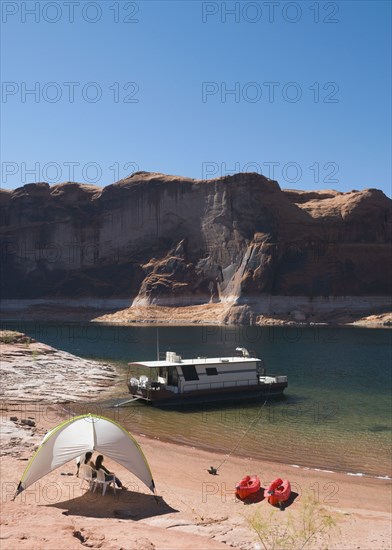 Friends sitting under tent next to houseboat