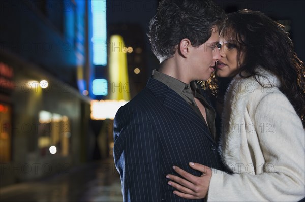 Elegant couple kissing on urban street at night