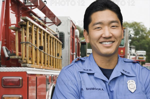 Asian firefighter next to fire truck
