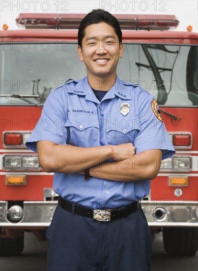 Asian firefighter next to fire truck