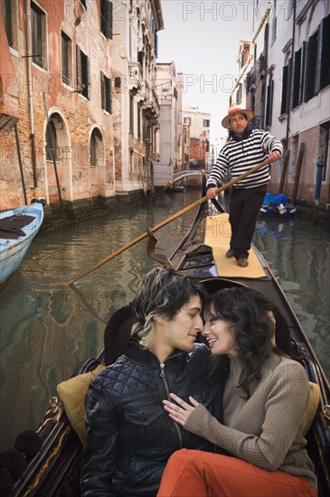 Romantic Italian couple riding in gondola through canal