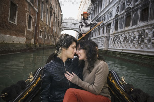 Romantic Italian couple riding in gondola through canal