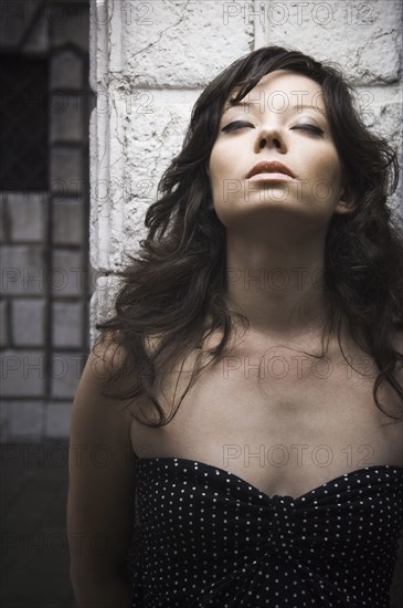 Italian woman leaning against wall with eyes closed