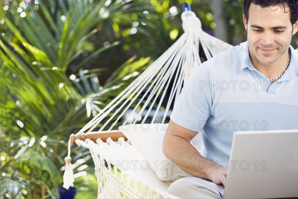 Mixed race man in hammock using laptop