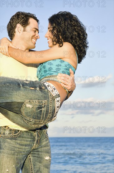 Mixed race couple playing on beach