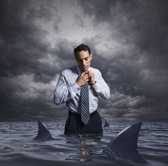 Latin businessman standing in shark infested waters