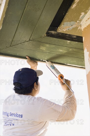 Latin man caulking roof eaves