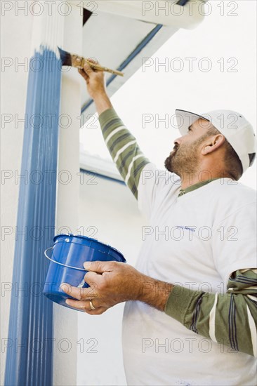 Latin man painting gutters