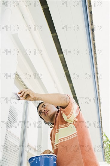 Latin man painting outside of house