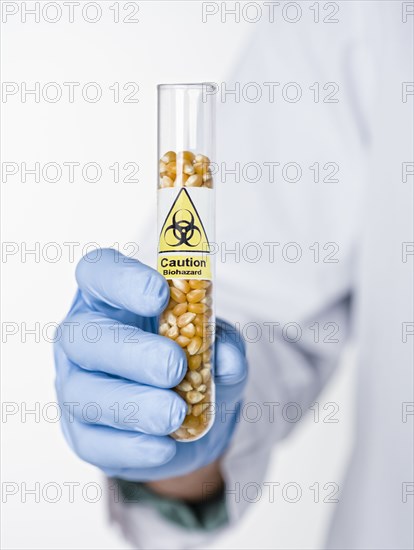 Hispanic scientist holding test tube with caution symbol containing