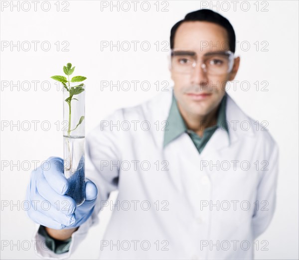 Hispanic scientist holding test tube containing sprout