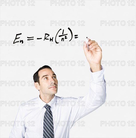 Hispanic businessman writing formula on clear board