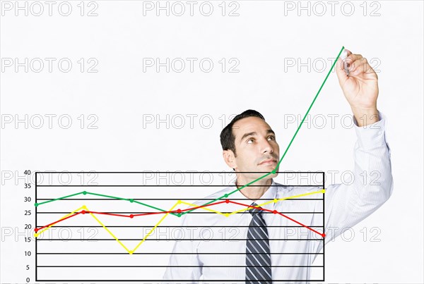 Hispanic businessman drawing chart on clear board