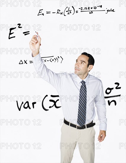 Hispanic businessman writing formula on clear board