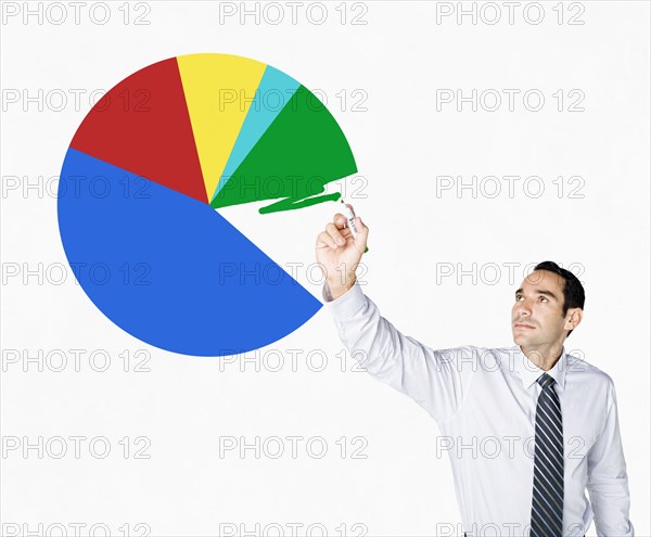 Hispanic businessman drawing pie chart on clear board