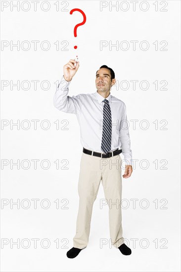 Hispanic businessman drawing question mark on clear board