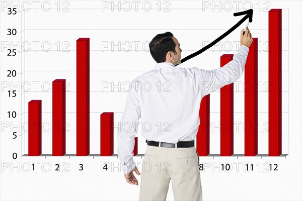 Hispanic businessman drawing bar graph on board