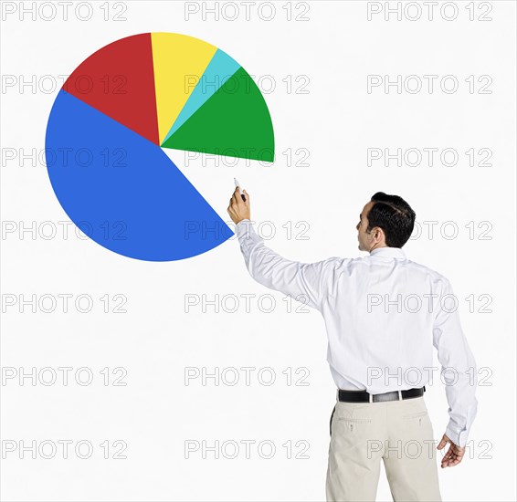 Hispanic businessman drawing pie chart on board