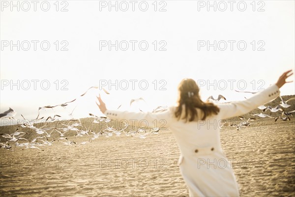 Woman scaring seagulls on beach