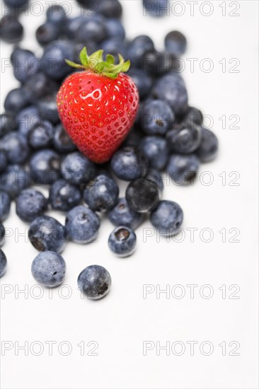Strawberry on pile of blueberries