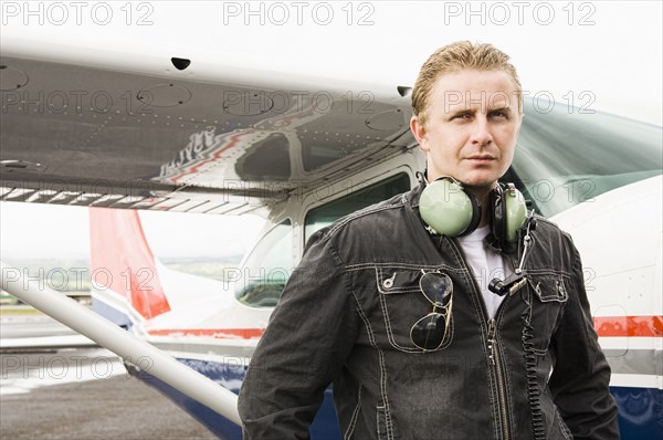 Caucasian pilot standing near small airplane