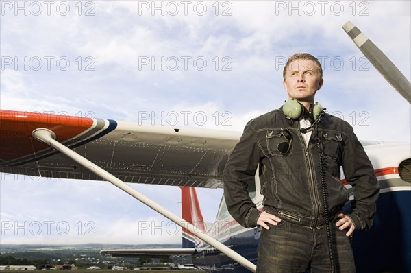 Caucasian pilot standing near small airplane