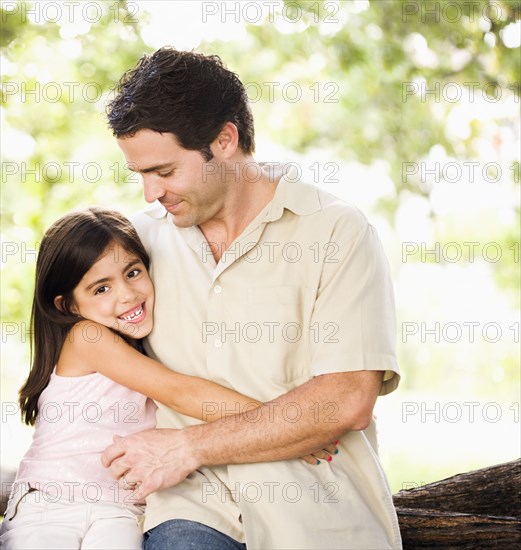 Mixed race father hugging daughter