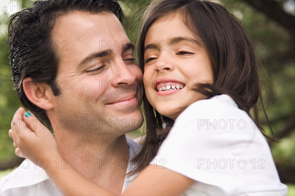 Mixed race father hugging daughter