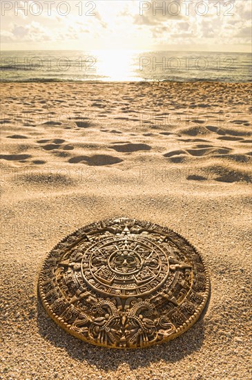 Aztec calendar stone carving on sandy beach