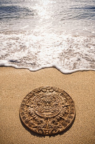 Aztec calendar stone carving on sandy beach