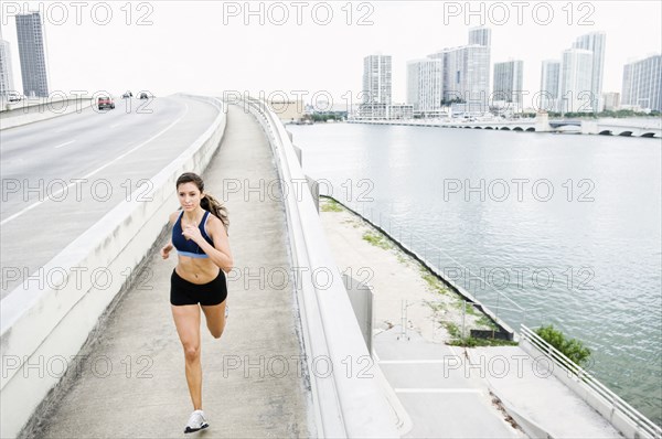 Hispanic woman running near urban waterfront