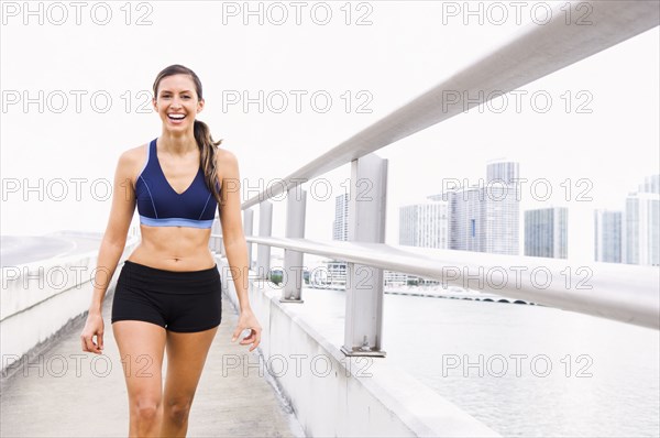 Hispanic woman in sportswear walking along urban waterfront