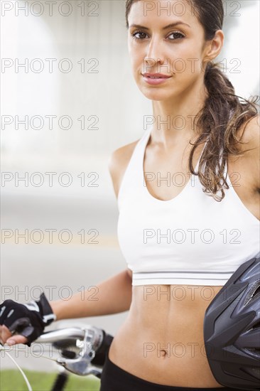 Hispanic woman standing with bicycle and helmet