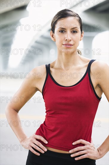 Hispanic woman in sportswear standing in urban area