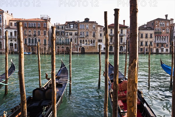 Gondolas moored in canal on wooden posts