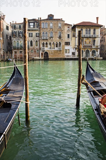 Gondolas moored in canal on wooden posts