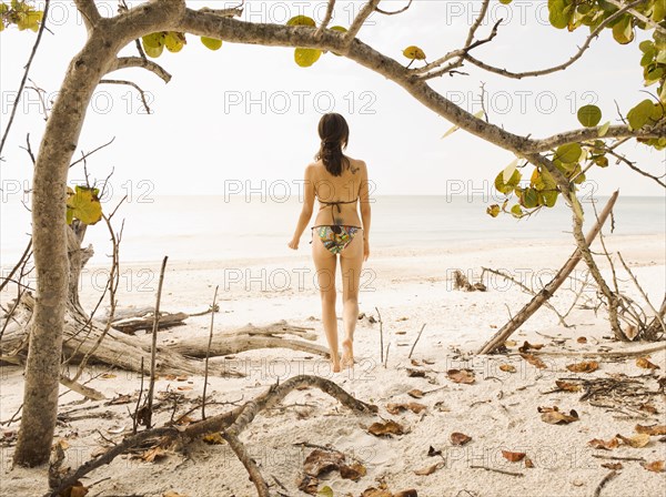 Hispanic woman in bikini standing on beach