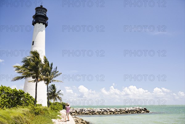 Lighthouse and tropical palm trees near ocean