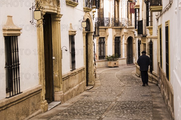 Man walking down cobblestone alley in quaint village