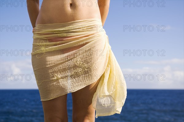 Hispanic woman wearing sarong near ocean